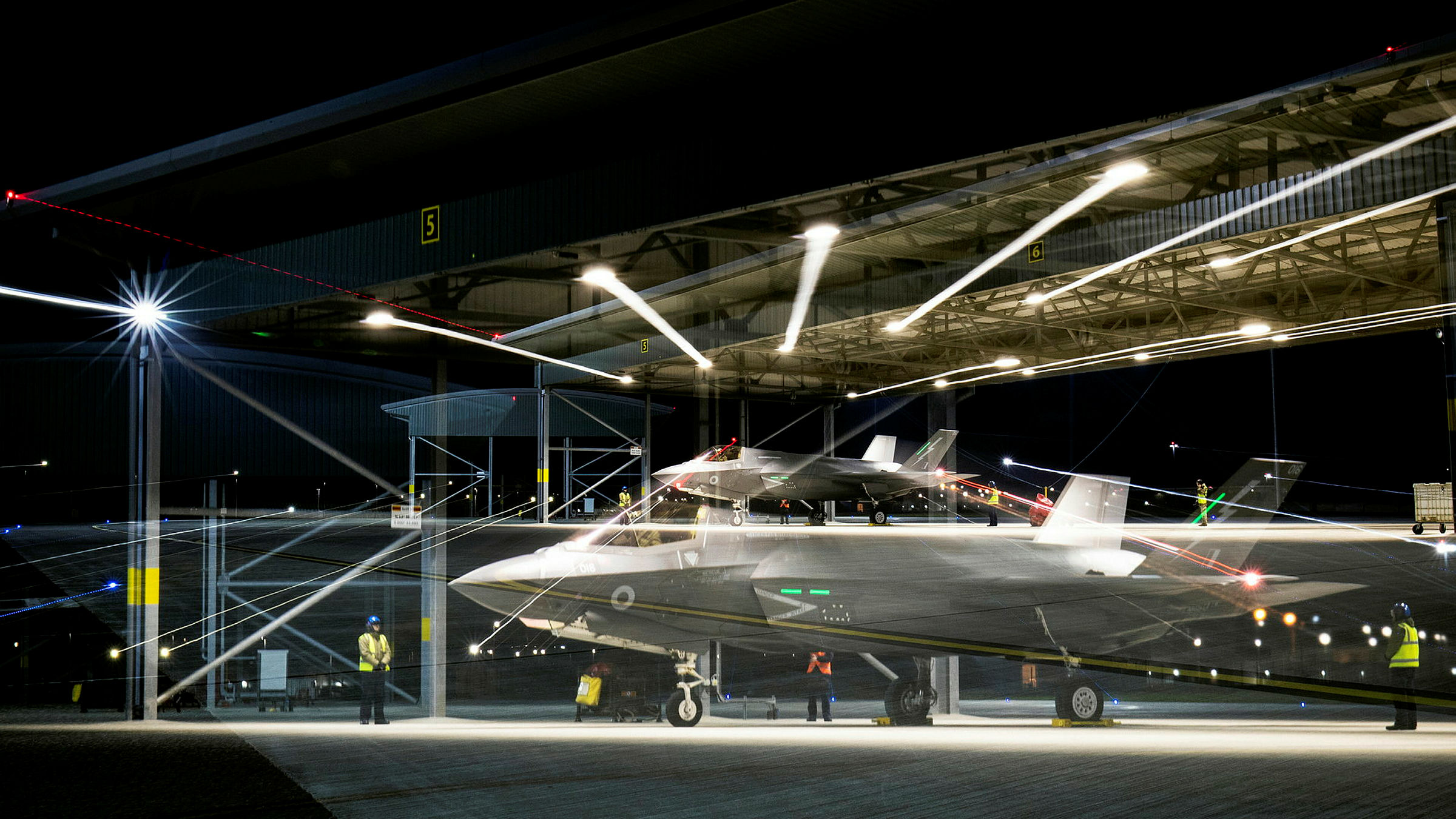 F-35B Lightning in a hangar, with lights and a hologram projection of the aircraft above.